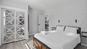 Ein modernes Schlafzimmer mit einem Bettgestell aus Holz, weißer Bettwäsche und einer Wand mit geometrischen Mustern.