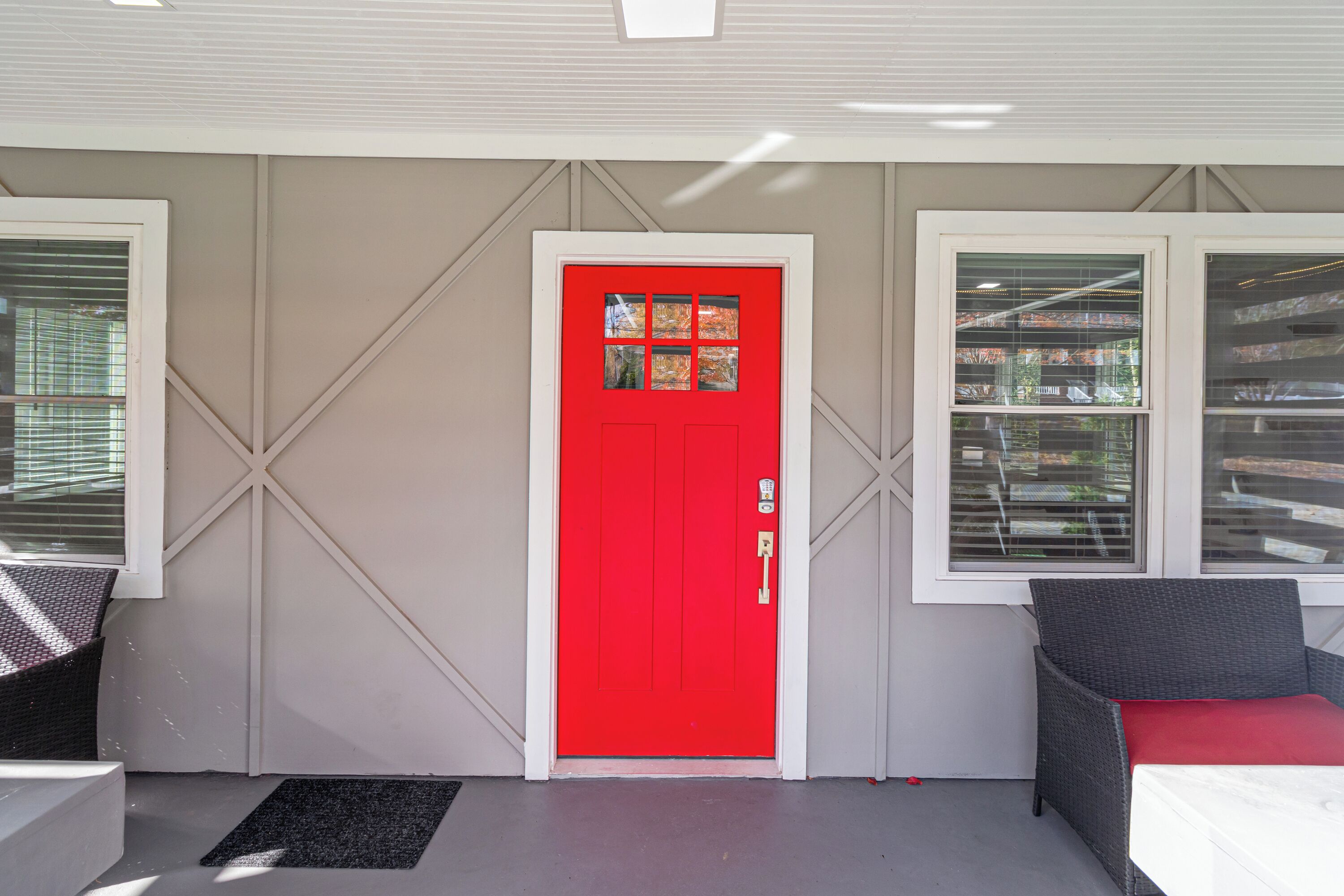 A red door with a window, a grey chair, and a white table.