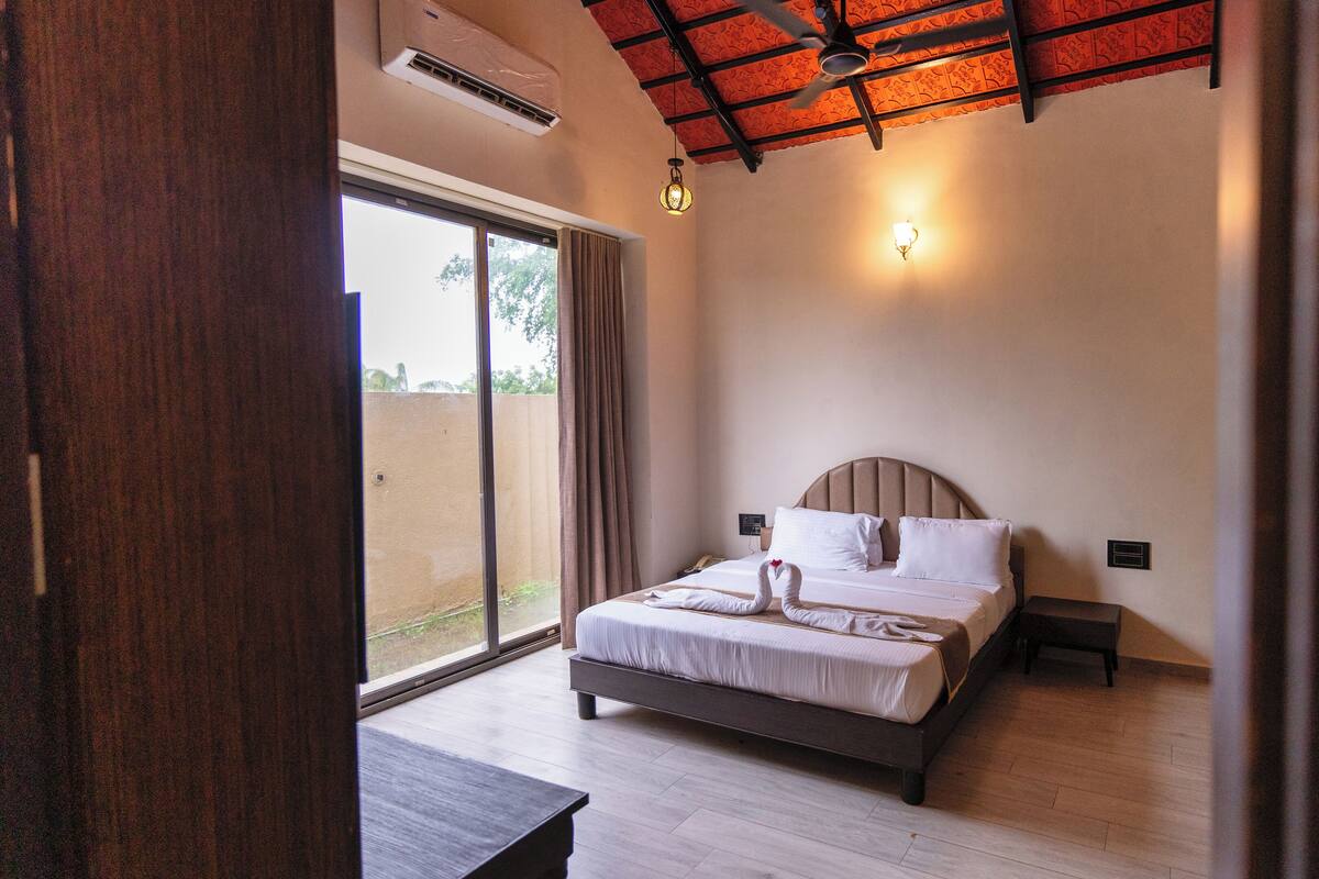 A bedroom with a bed, bedside tables, a ceiling fan, and a view through a sliding glass door.