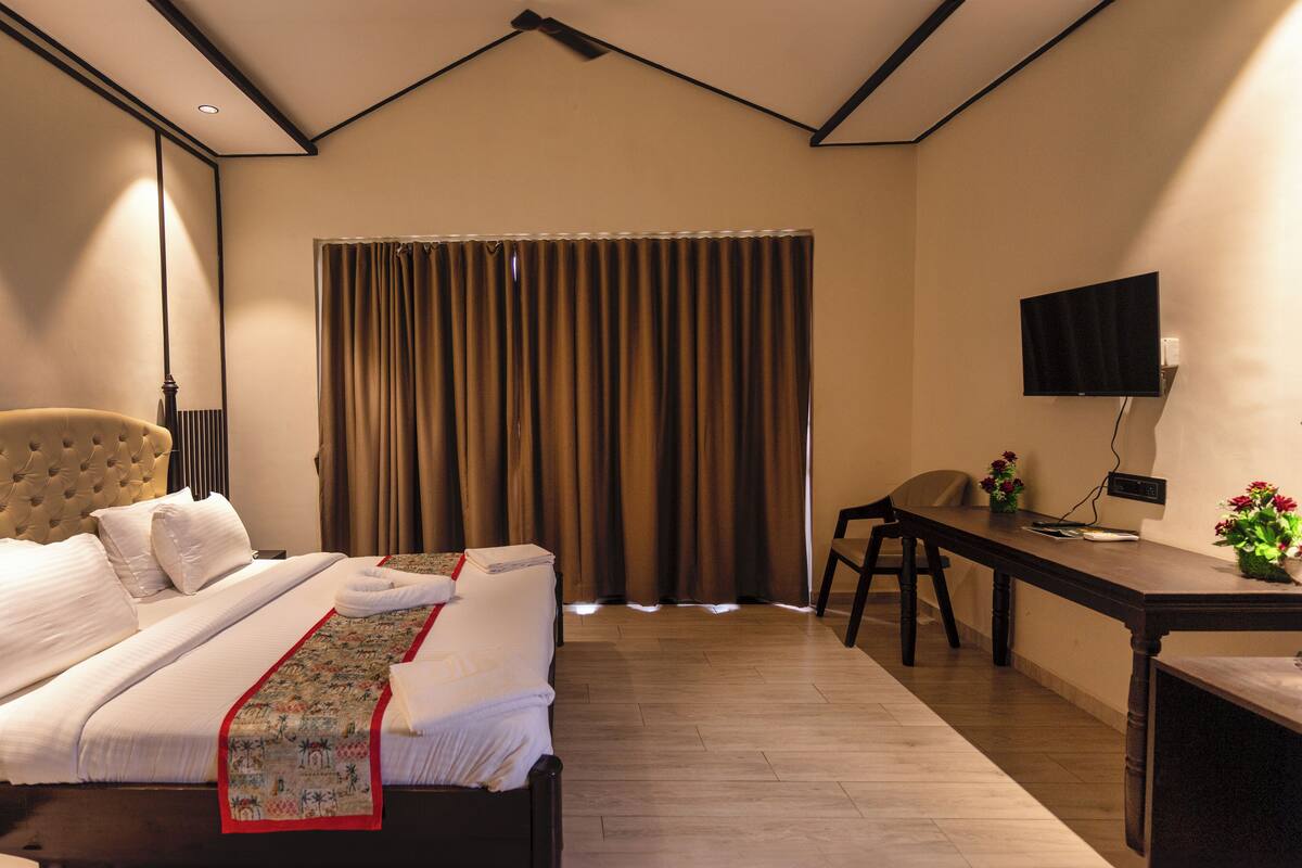 A hotel room with a large bed, a desk, a chair, and a television.