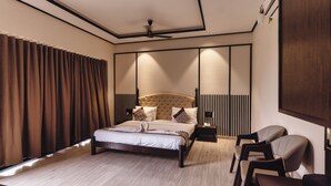 A modern bedroom with a large bed, a bedside table with a phone, and a chair. - The premier gir resort (Talala)