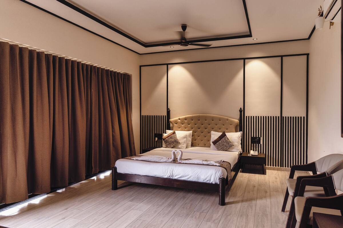A modern bedroom with a large bed, a bedside table with a phone, and a chair.