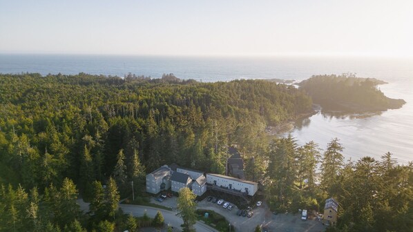 An aerial view of a forested area with a building complex near a body of water.