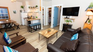 Un salon moderne avec un canapé en cuir marron, une table basse en bois et un téléviseur.
