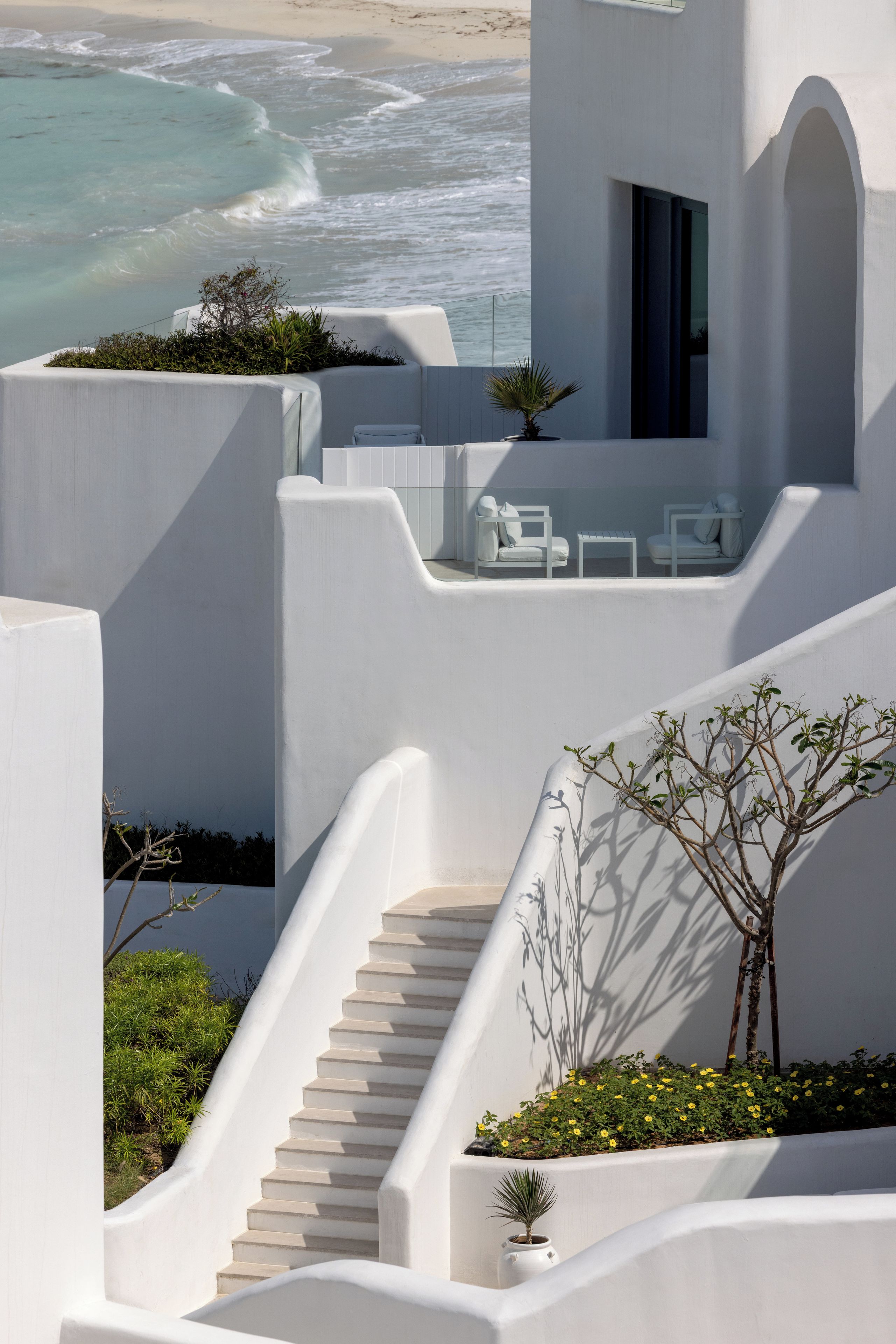 Un design architectural moderne, avec un escalier menant à un balcon d’où l’on a une vue sur l’océan.