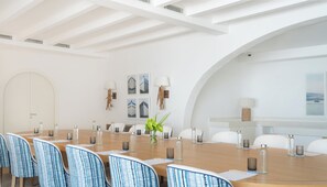 Un salón de conferencias con una mesa larga, sillas y un amplio ventanal de arco.