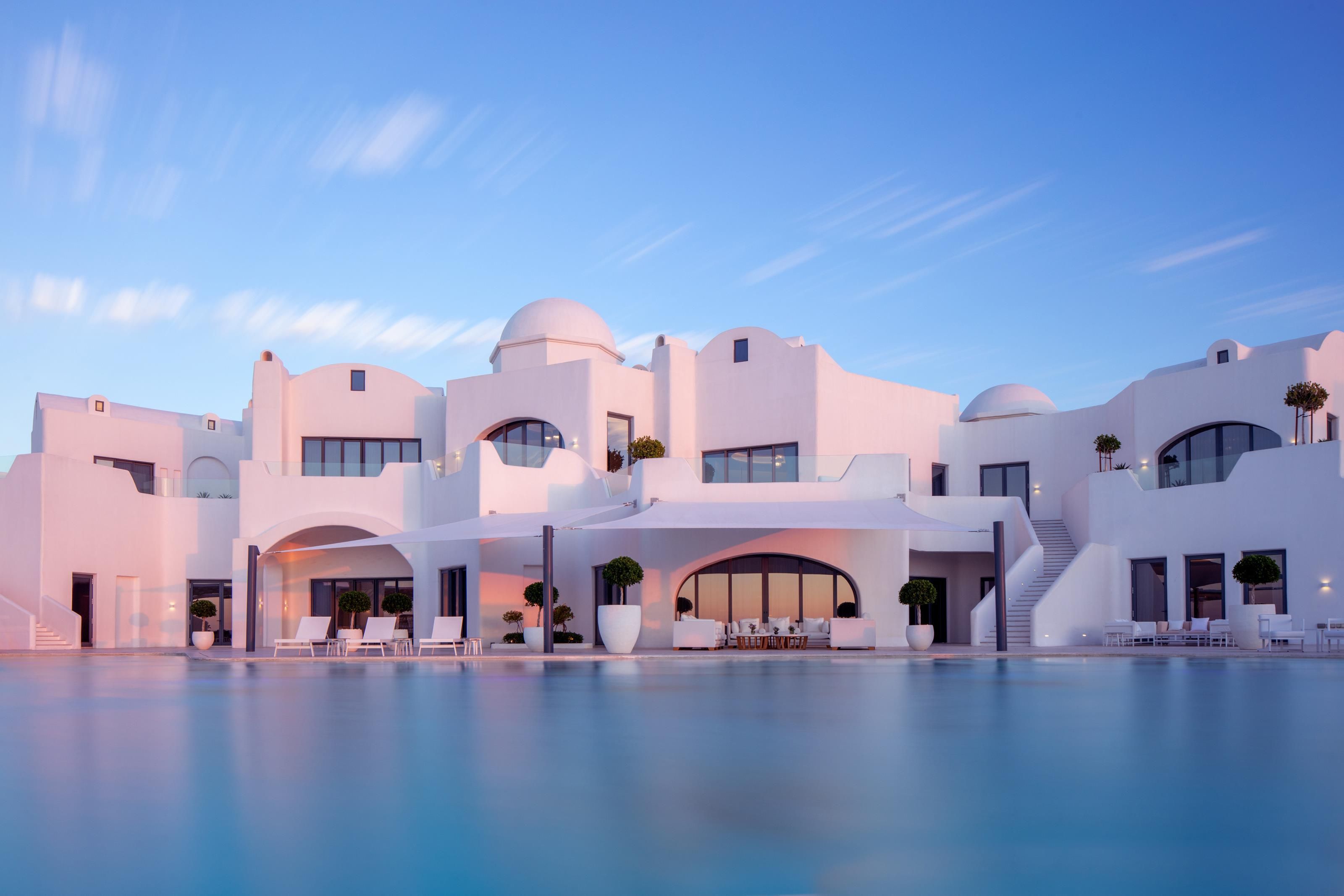 Un bâtiment moderne de couleur blanche, avec une piscine devant.