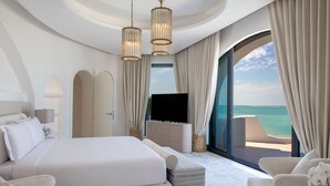 A modern bedroom with a large bed, a TV, and a view of the ocean. - Anantara Retreat Santorini Abu Dhabi - Adults Only (Ghantoot)
