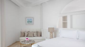 A hotel room with a bed, a sofa, a round table, and a lamp.
