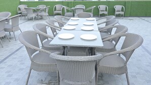 Una terraza en la azotea con mobiliario de mimbre y una mesa larga para seis personas.