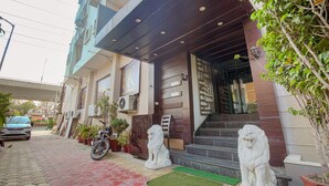 Un edificio con entrada moderna, una motocicleta estacionada afuera y dos estatuas de leones en la entrada.