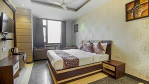 Una habitación de hotel moderna con una cama grande, televisor, escritorio y ventana con cortinas.