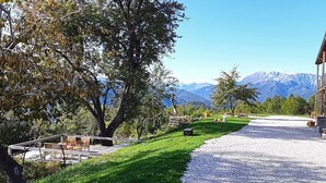 Une maison avec une allée en gravier, une terrasse en bois et une vue sur la montagne.