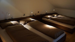 Une chambre avec trois lits disposés en rangée, chacun muni d’une tête de lit et de lampes de chevet.