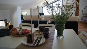 Une table à manger avec une assiette de nourriture, un vase rempli de fleurs et une bougie.