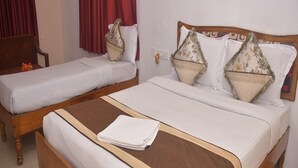 Una cama doble con estructura de madera y una colcha blanca, flanqueada por dos camas individuales de diseño similar.