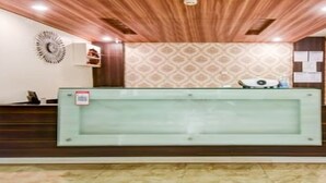 Un mostrador de recepción con separador de vidrio, paneles de madera en las paredes y un diseño de papel tapiz estampado.