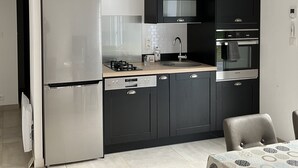 A modern kitchen with a stainless steel refrigerator, a built-in microwave, a gas stove, and a double oven.