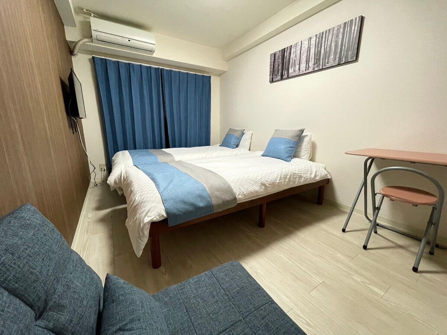 A hotel room with a bed, a desk, a chair, and a painting on the wall.