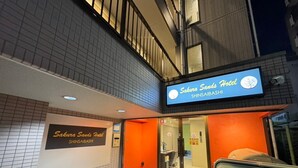 Das äußere Erscheinungsbild des Sakura Sands Hotels, mit einem Schild, das den Namen und den Ort angibt.
