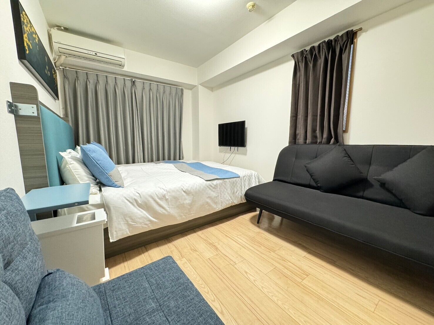 A room with a bed, a sofa, a TV, and a desk.