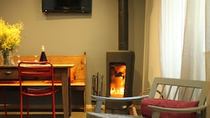 Una sala de estar acogedora con chimenea, televisor montado en la pared y disposición de asientos que incluye un sofá y una butaca.