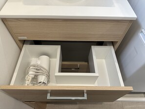 A modern kitchen with a wooden countertop and a drawer containing a white appliance, a cylindrical container, and coiled cables. - SolanaFujiyamanakako (Yamanakako)