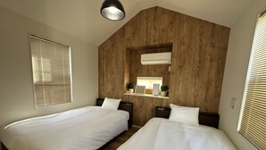 A bedroom with two beds, wooden paneling on the wall, a shelf with a mirror, and an air conditioning unit. - SolanaFujiyamanakako (Yamanakako)