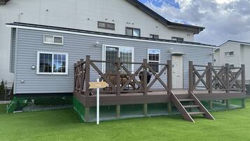 A two-story building with a deck and a sign pointing to the right.