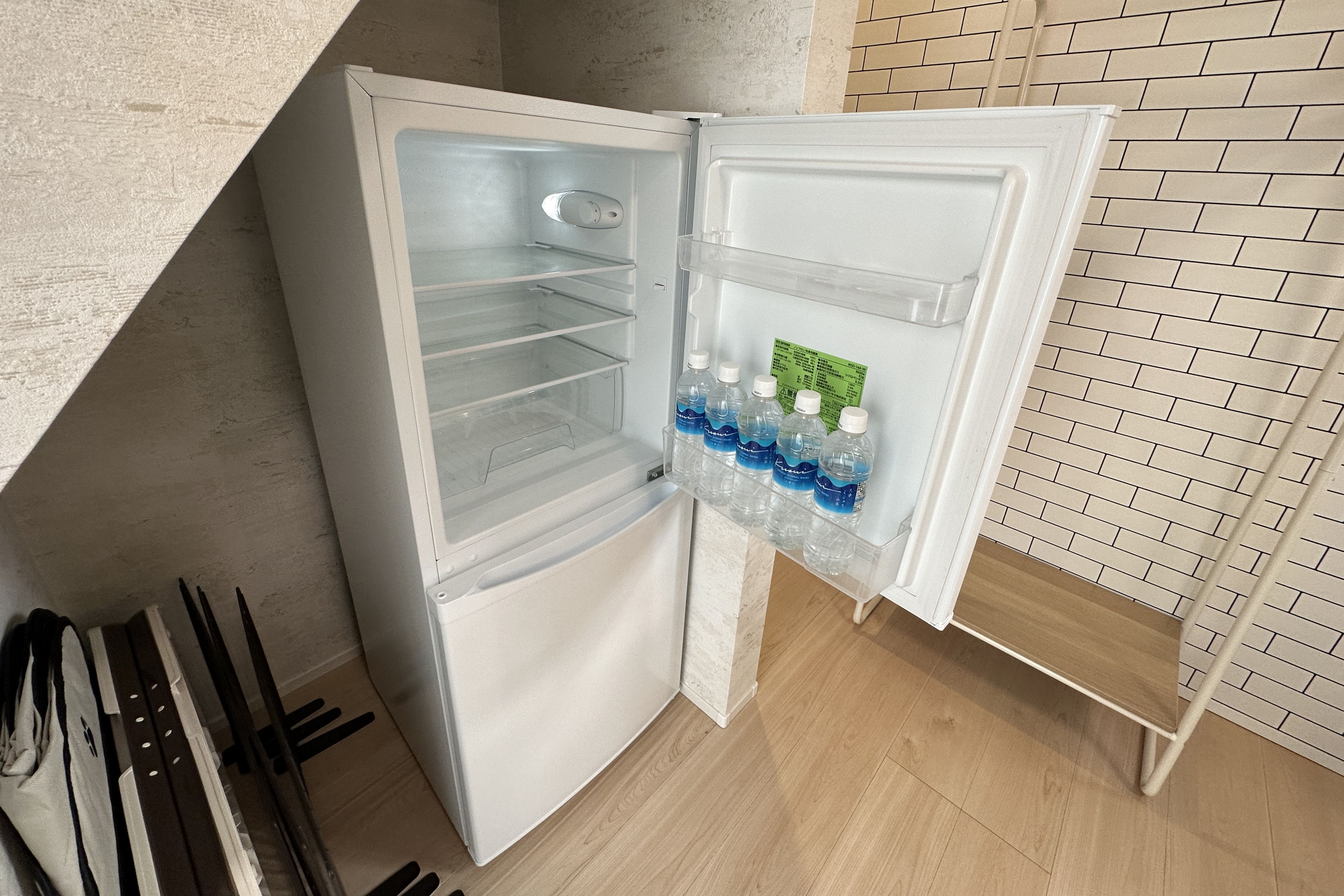 Un réfrigérateur blanc doté d’un compartiment congélateur, d’un distributeur d’eau et d’une étagère pour les bouteilles d’eau.