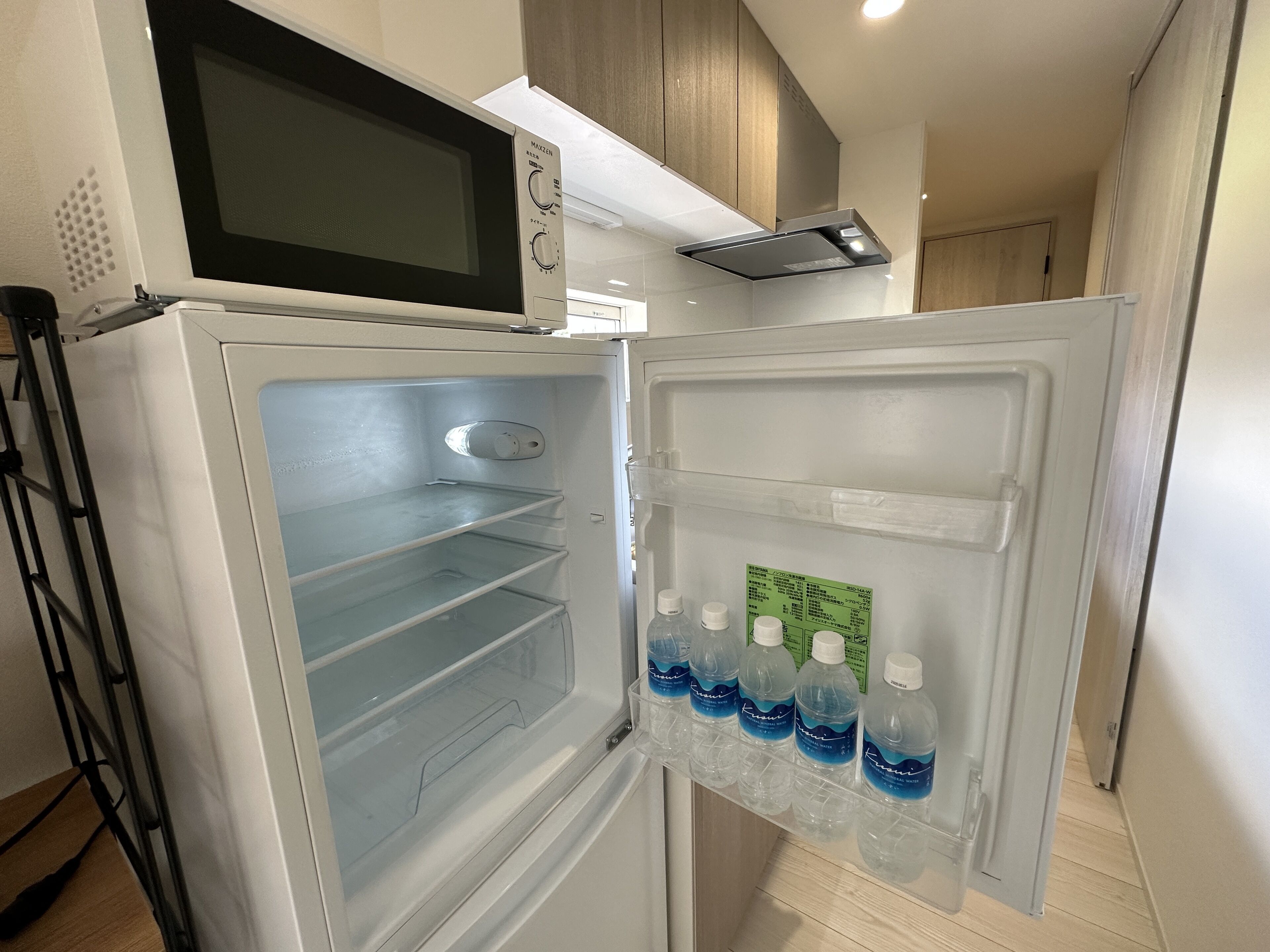 A modern kitchen with a built-in microwave, an empty refrigerator, and a water dispenser.