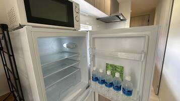 A modern kitchen with a built-in microwave, an empty refrigerator, and a water dispenser.