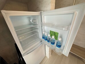 Un réfrigérateur ouvert, avec des étagères transparentes et un distributeur d’eau.