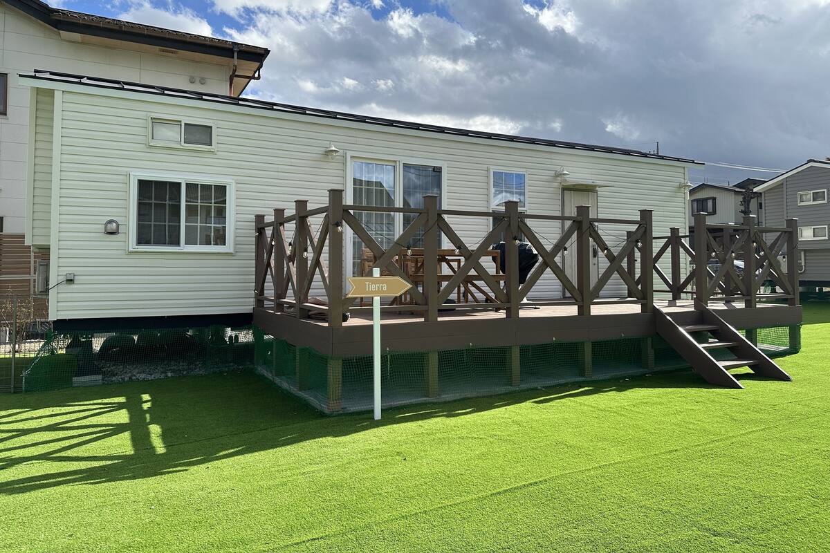 Una casa móvil con una terraza cercada y un letrero que dice 'Tierra'.