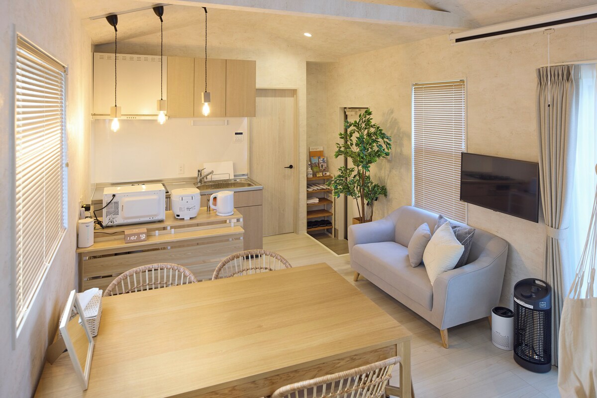 A modern kitchen with a dining area, a sofa, and a TV.