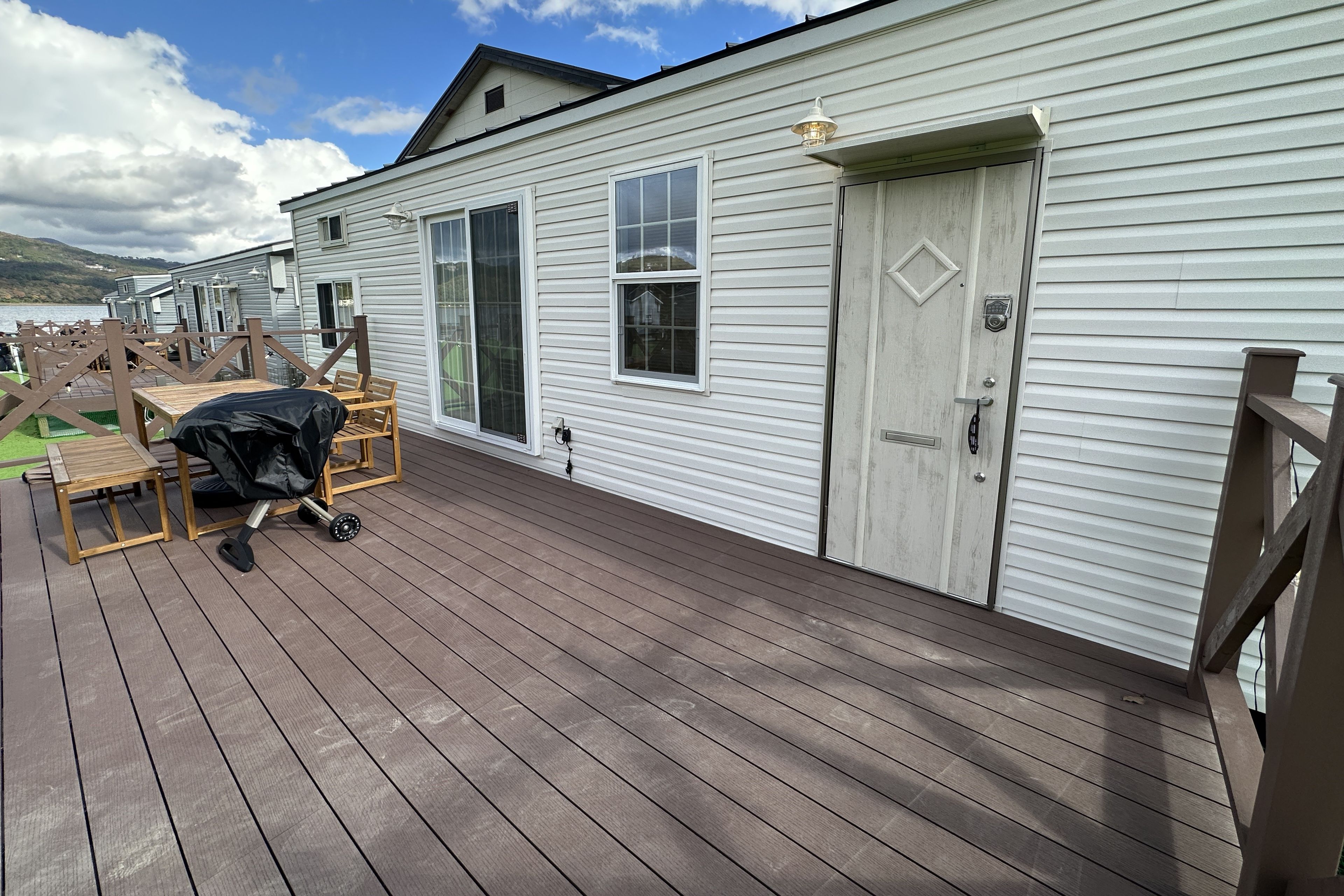 A residential deck with a covered outdoor seating area, a sliding door, and a view of a lake.