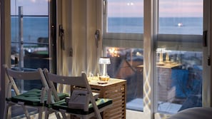 A balcony with a chair, a table with a lamp, and a view of the sea. - Pohang Sevenstay (Pohang)