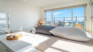 A modern hotel room with a large balcony, a plush sofa, a dining table with wine glasses, and a teddy bear. - Pohang Sevenstay (Pohang)