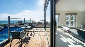 A balcony with a wooden deck, a pool, and a seating area with a sofa and a table. - Pohang Sevenstay (Pohang)