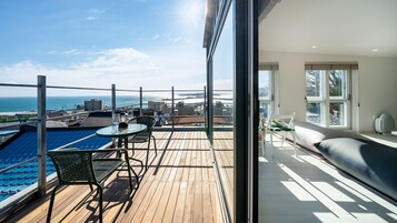 A balcony with a wooden deck, a pool, and a seating area with a sofa and a table.