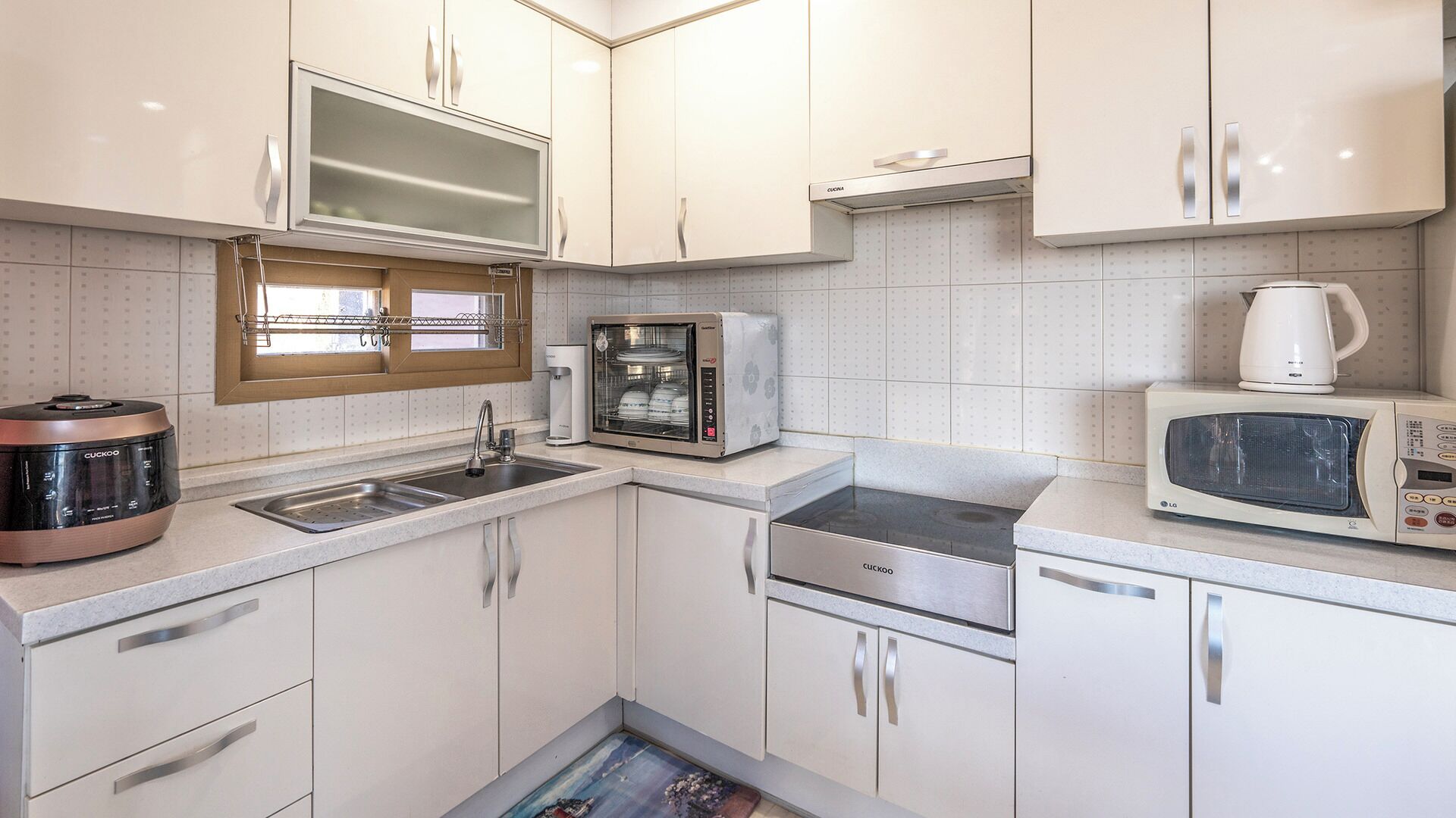 A compact kitchen with a sink, a dishwasher, a microwave, a coffee maker, and a food processor.