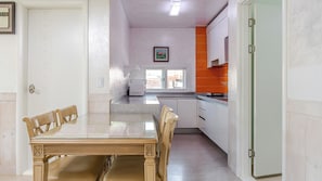 Un comedor con una mesa y sillas, una cocina con armarios color naranja, y un ventanal con vistas.