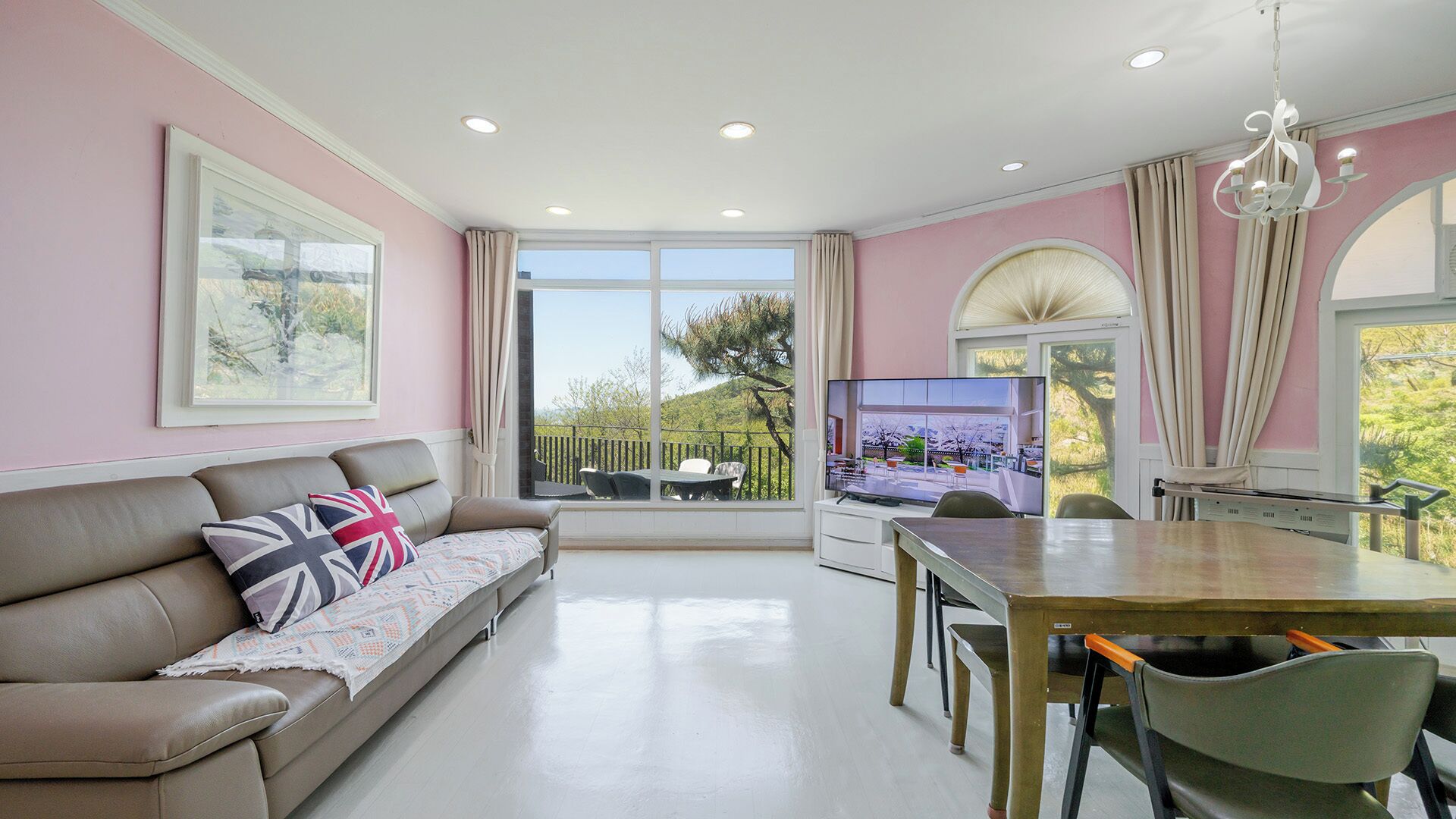 Una sala moderna con sofá, televisor, mesa de comedor y sillas.