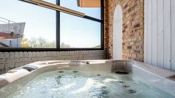 A hot tub with a view of a brick wall and a window.