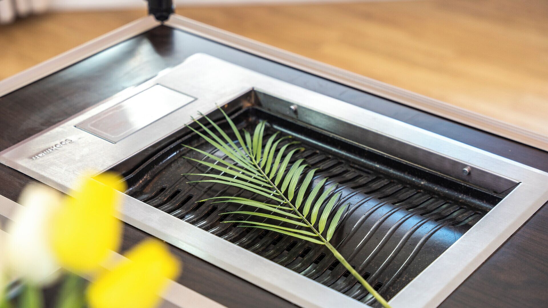 A stainless steel grill with a leaf and a metal plate.