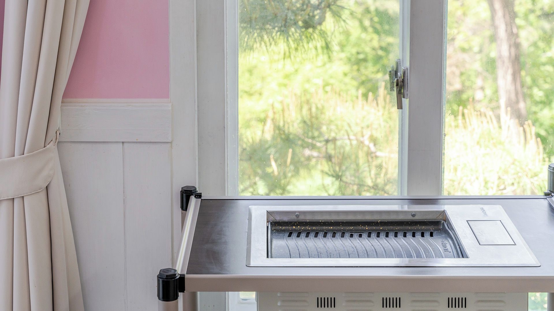 A room with a window, a curtain, and a control panel.