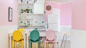 A kitchen with a white countertop, a sink, and a refrigerator. There are colorful chairs and a clock on the wall. - Ganghwa Sky Garden Poolvilla (Incheon)
