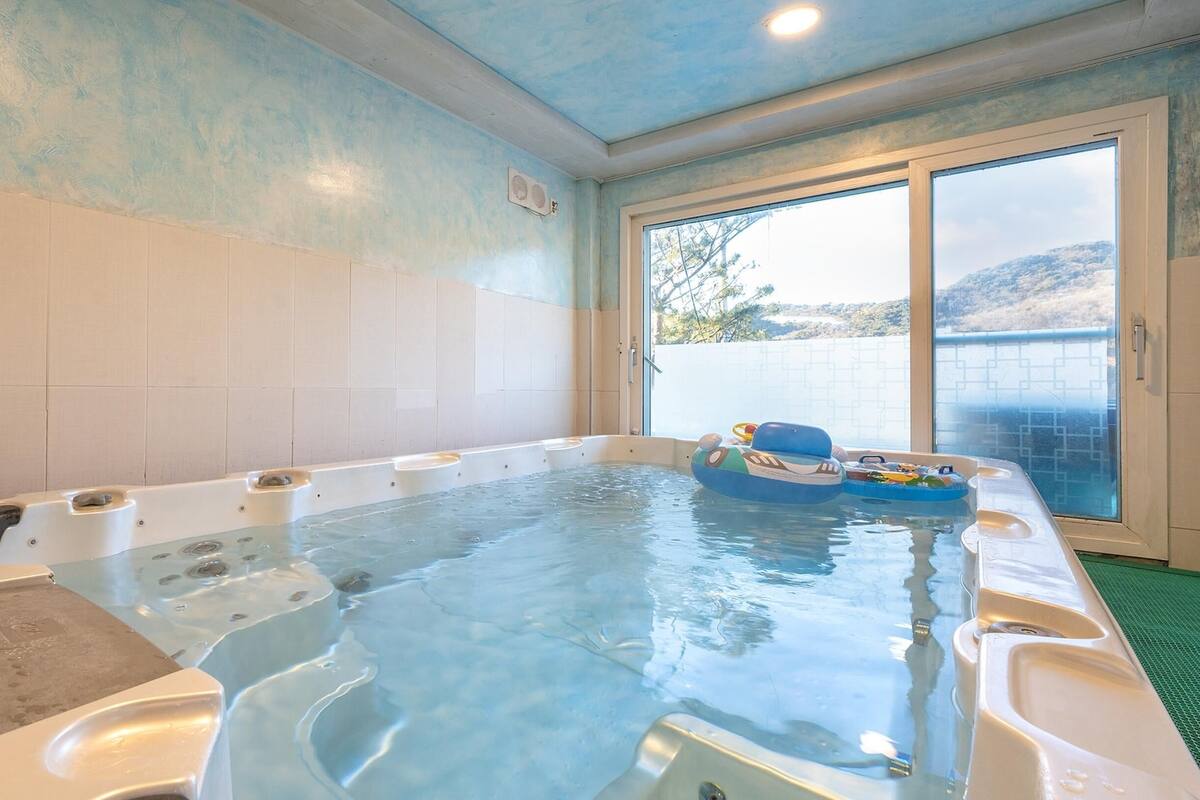 Un jacuzzi con varias zonas de estar y vistas al exterior a través de un ventanal corredizo.