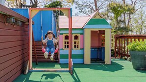 A child on a swing in a colorful playground with a small house structure. - Ganghwa Sky Garden Poolvilla (Incheon)