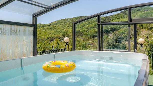 A glass-enclosed hot tub with a yellow inflatable ring, surrounded by a metal railing and two spherical lights. - Ganghwa Sky Garden Poolvilla (Incheon)